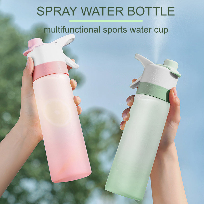 Two spray water bottles, one pink and one green, held by hands with a blurred outdoor background.