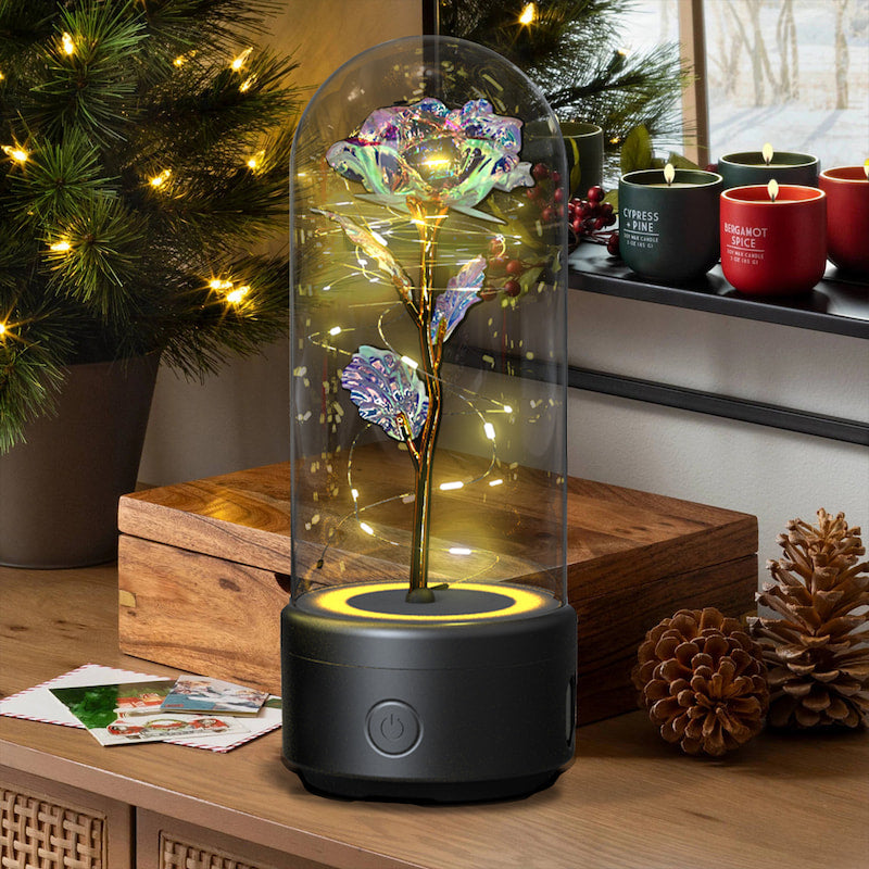 Decorative LED rose under a glass dome on a wooden surface with Christmas decorations.