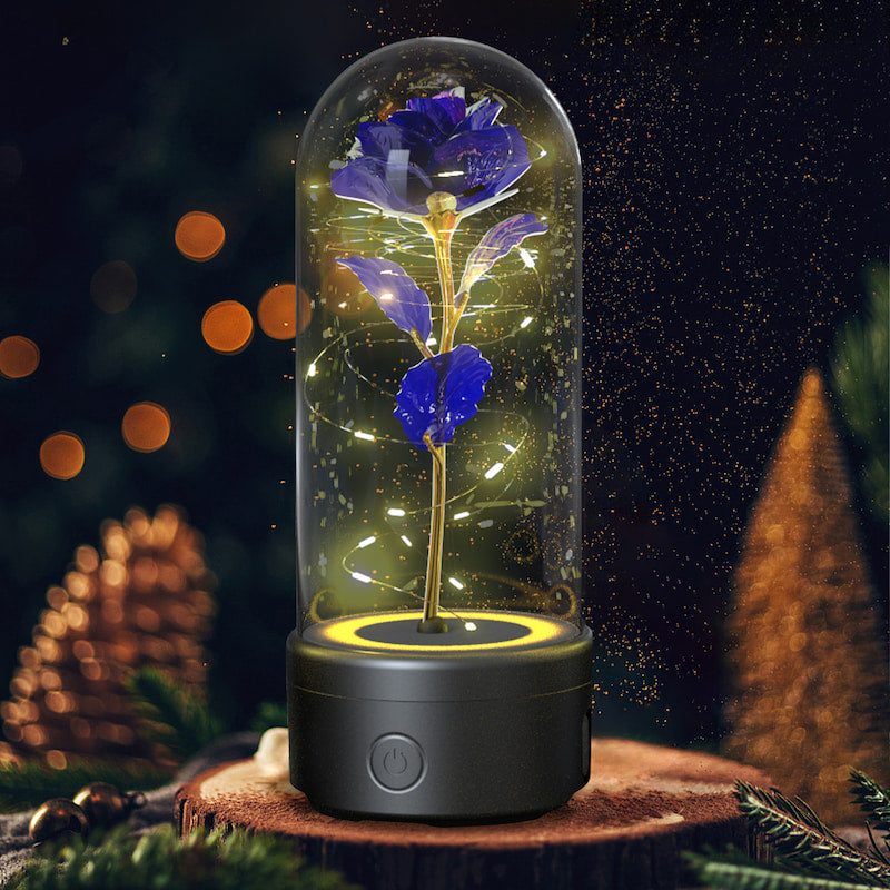Decorative lamp with a blue flower inside a glass dome on a wooden base with a dark, starry night background.
