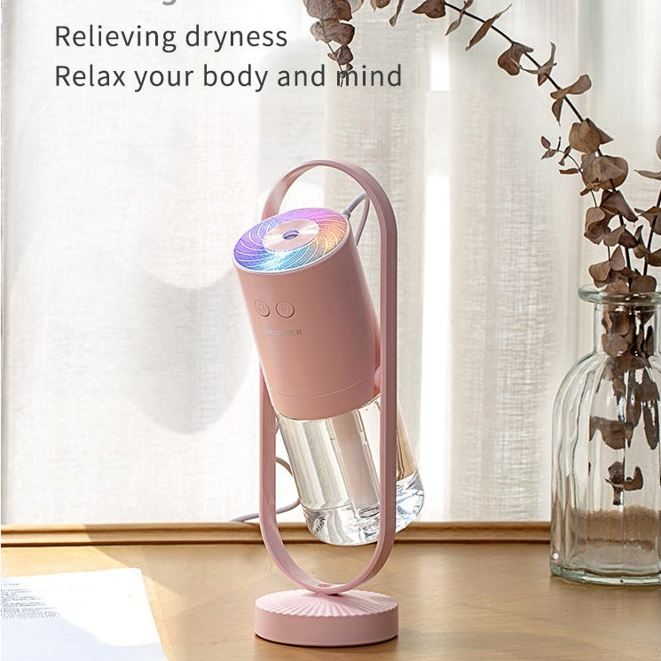 Pink humidifier with colorful light on a wooden surface with a blurred background