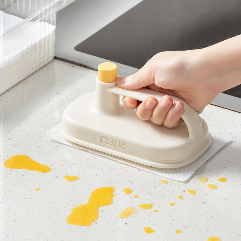Hand using a beige and yellow cleaning tool on a surface with yellow spots.