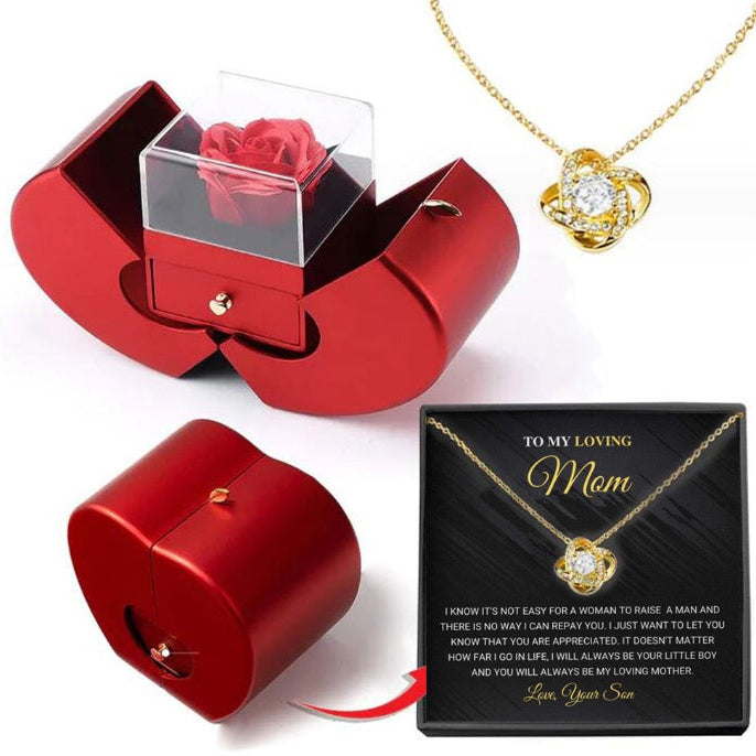 Red jewelry box with a rose, gold necklace, and black card for 'Mom' on a white background