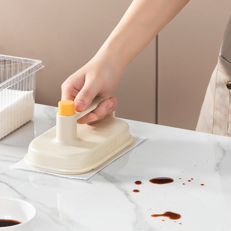 Person using a kitchen tool to clean up a spill on a countertop.