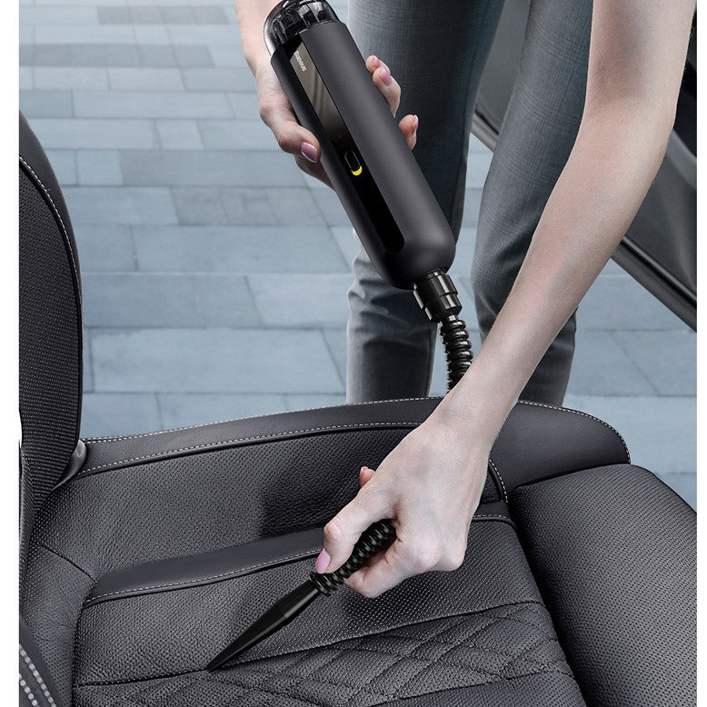 Person cleaning car seat with a handheld vacuum cleaner.