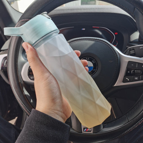 Hand holding a collapsible water bottle in front of a car steering wheel with BMW logo.