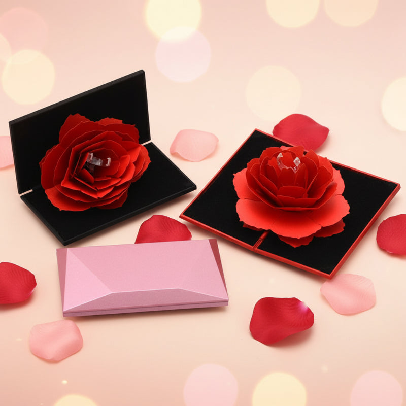 Two red roses in black boxes with a pink card on a white background