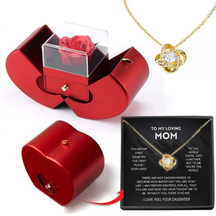 Red jewelry box with a heart-shaped design, gold necklace with heart pendant, and card for mom on a white background.