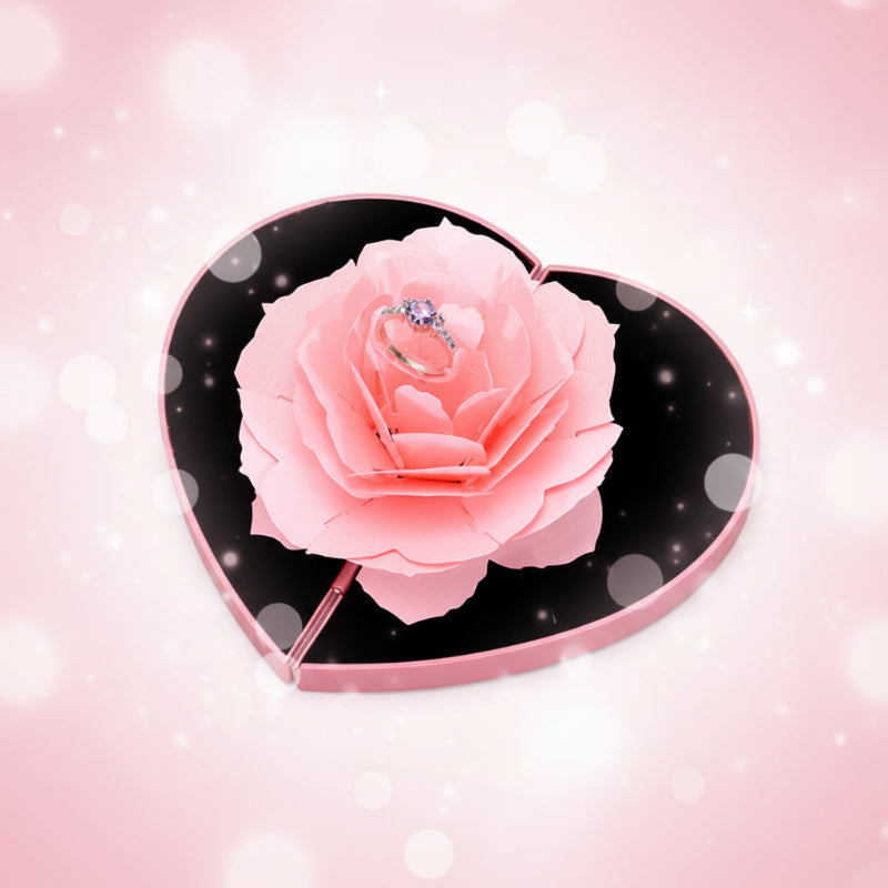 Heart-shaped box with a pink rose and a ring on a white background
