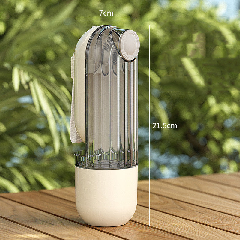 Transparent spray bottle with white base on a wooden surface, measuring 7cm and 21.5cm, with a blurred green outdoor background.