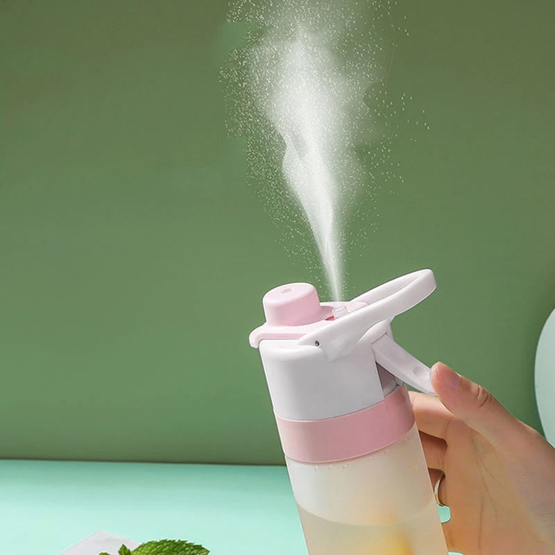 Hand holding a pink and white spray bottle with mist against a green background