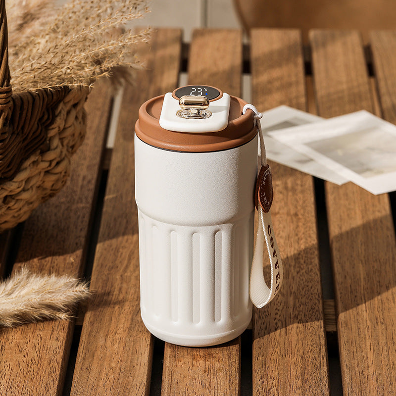 White travel mug with brown lid on a wooden surface