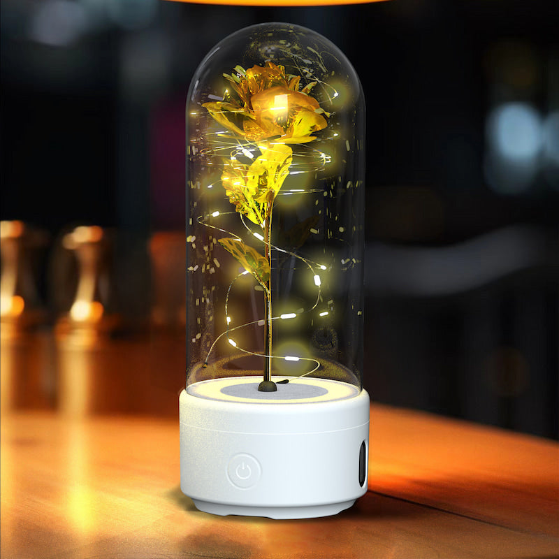 Decorative lamp with a gold rose inside a glass dome on a wooden surface.